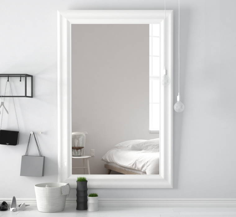 Ein Spiegel in einem Wohnzimmer auf einer grauen Wand hängend