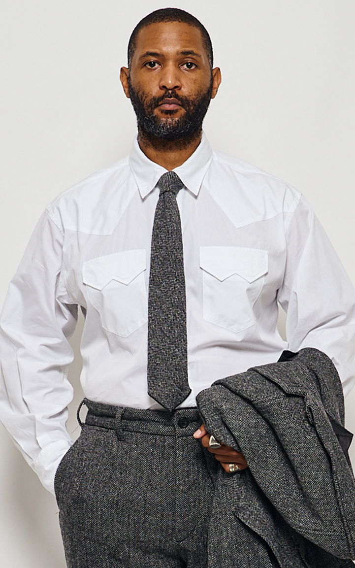 Man in a white shirt and tie holding a gray jacket.