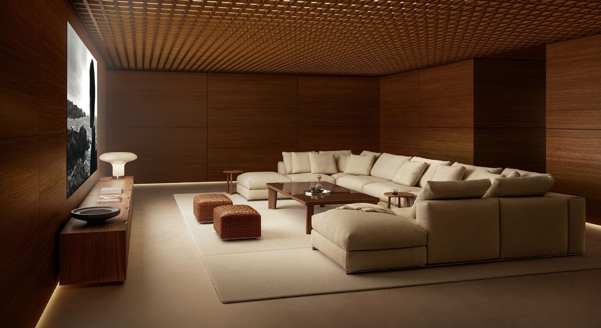 Modern living room with beige Flexform couch, wooden walls, and large television.