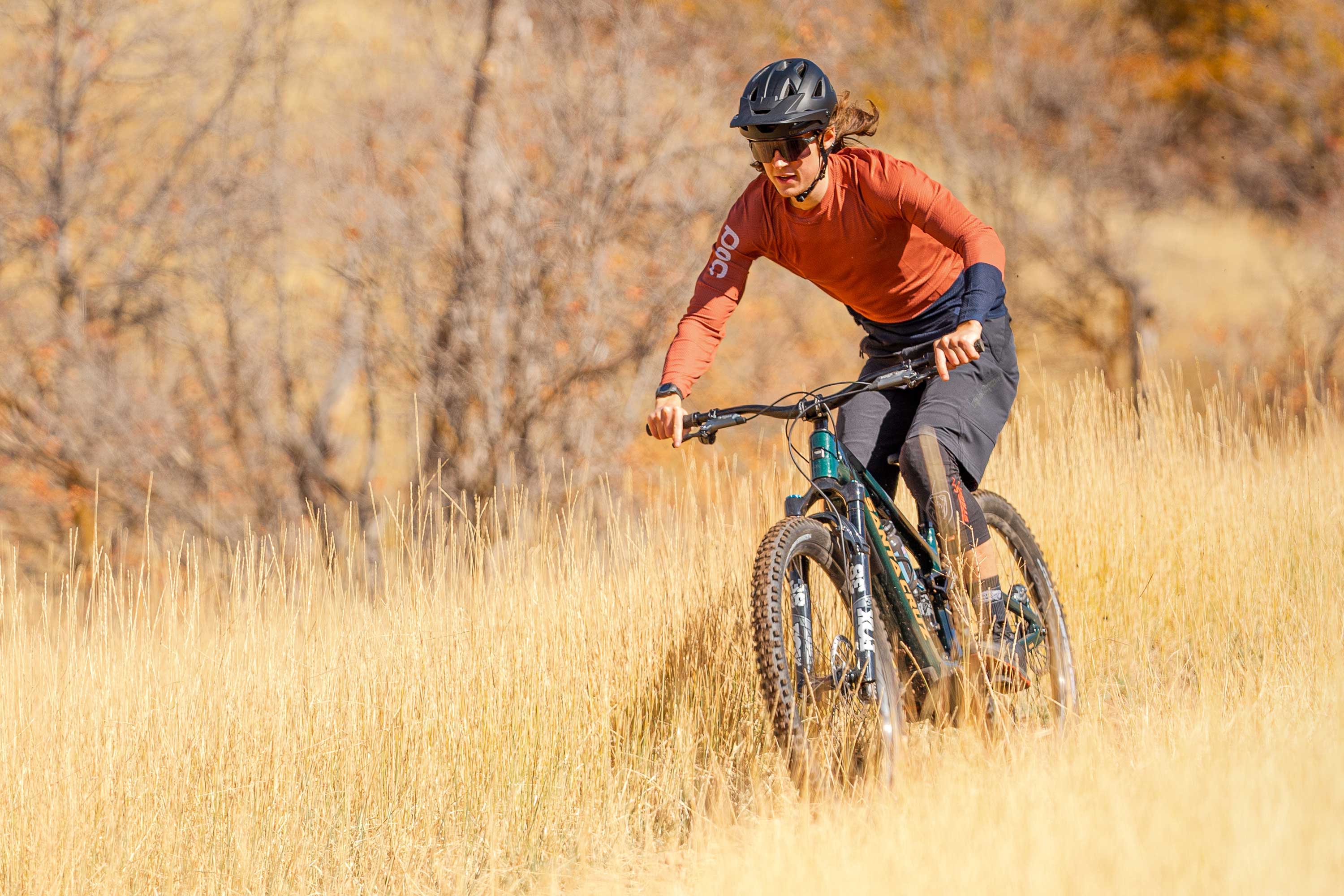 Mountain biker riding an electric mountain bike through a grass field.