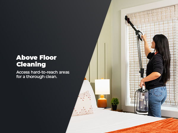 Woman using a vacuum cleaner to clean above the floor in a room.