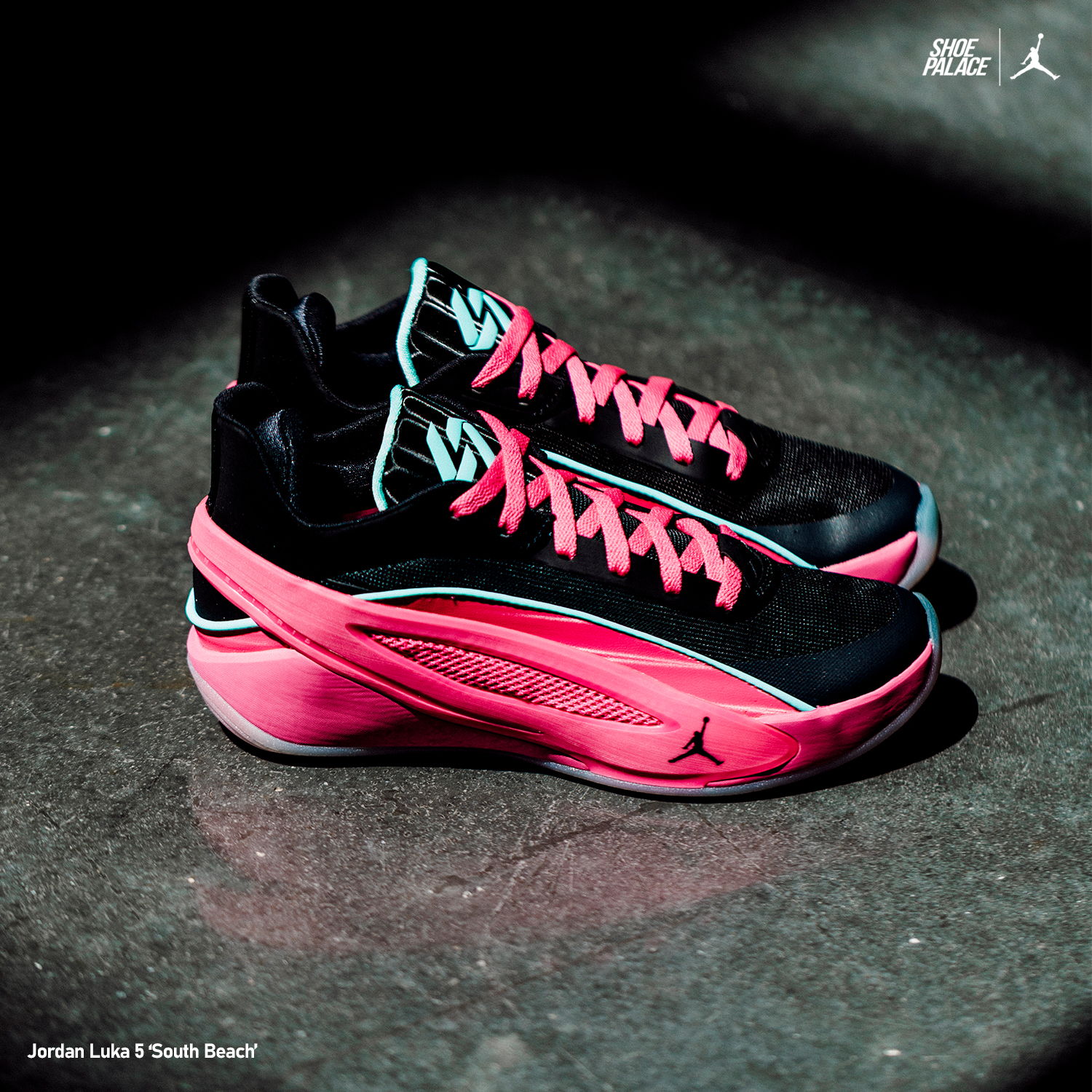 Black and pink athletic shoes on a textured surface.