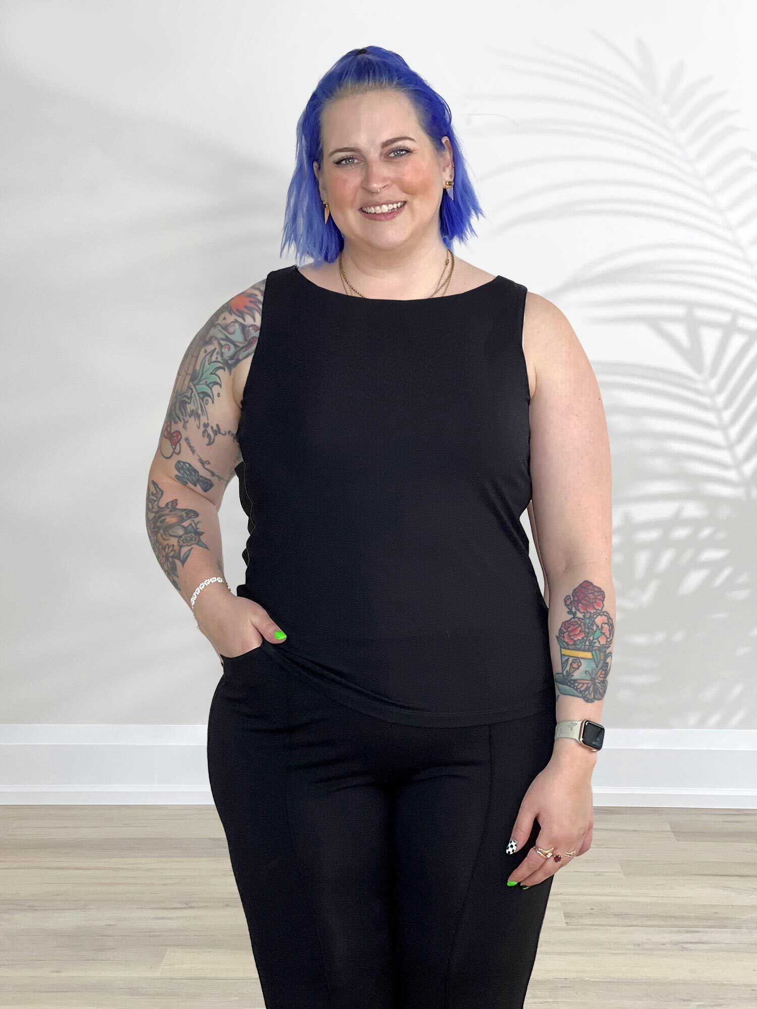 Woman standing wearing Miik's Eline reversible shelf bra tank in black with leggings