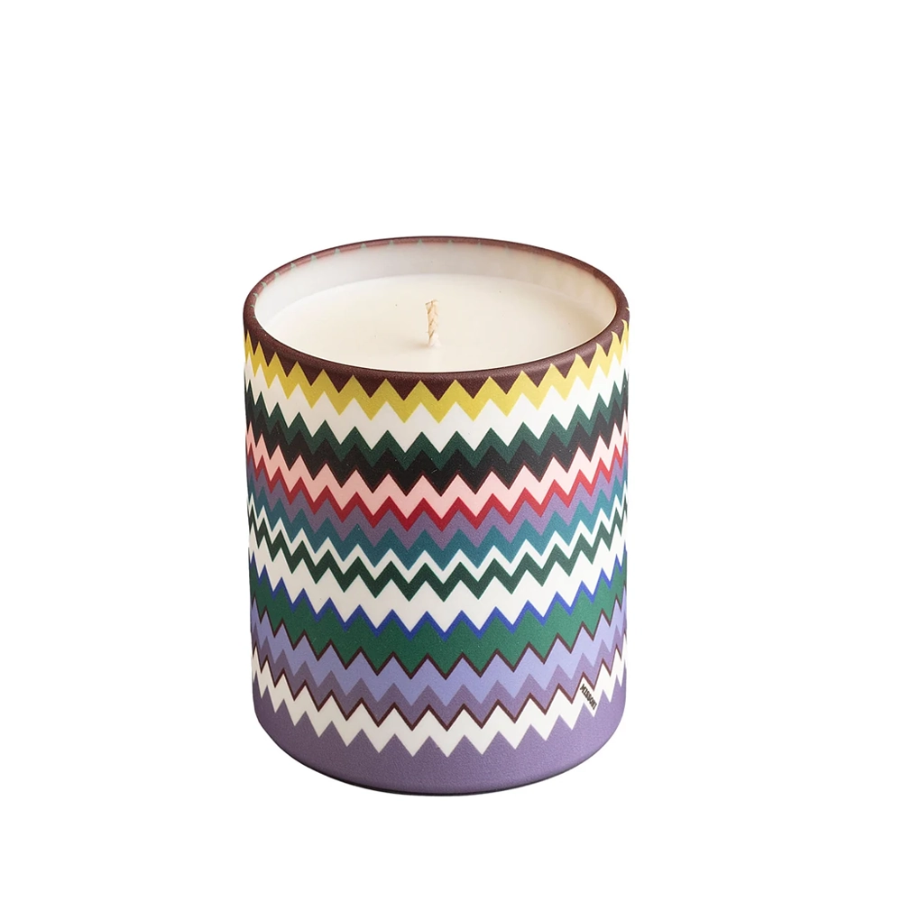 A colorful patterned candle in a round container.