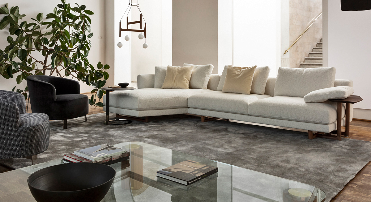 Modern Porada sofa with cushions, plant, and floor lamp in a bright room.