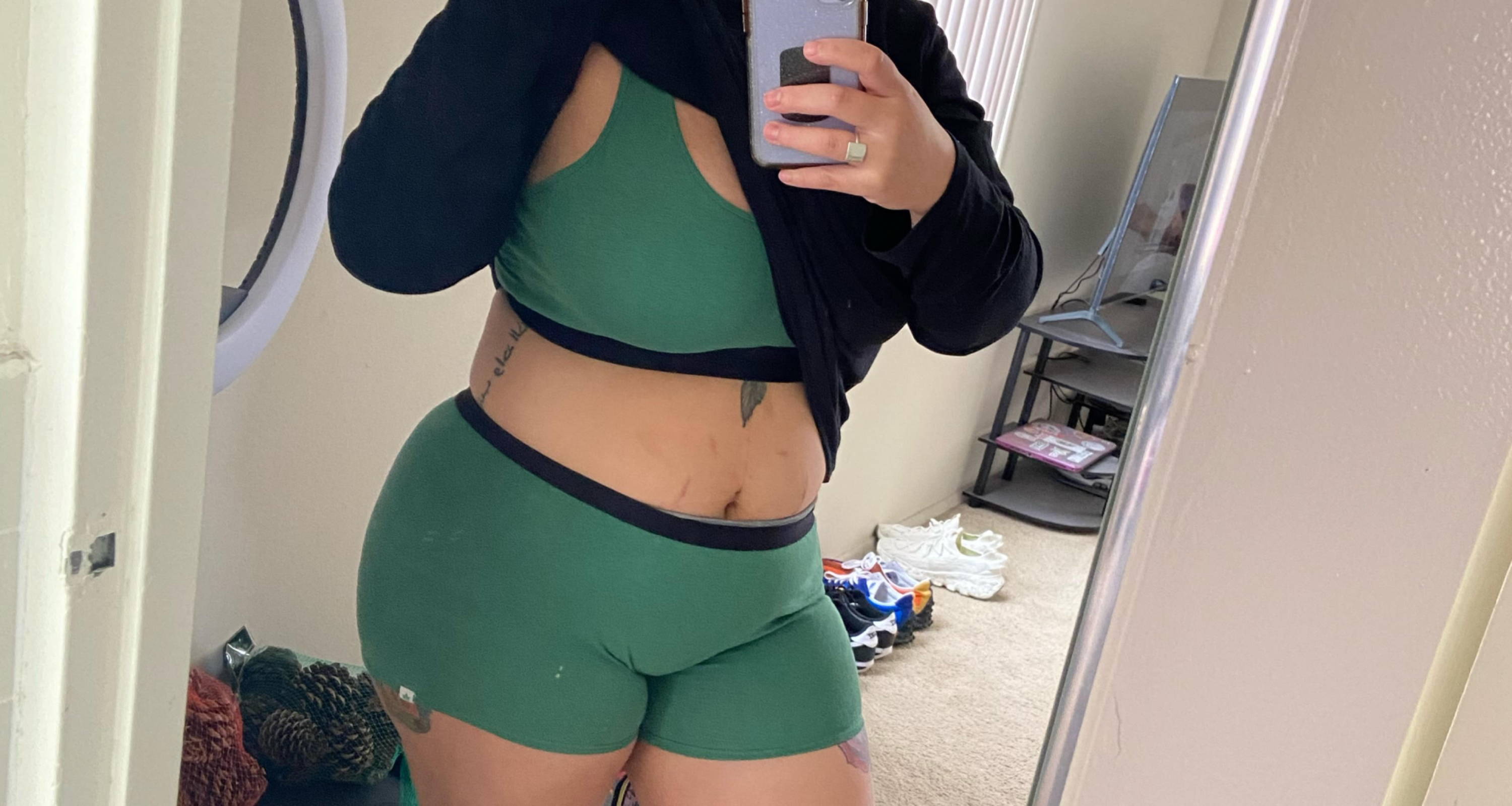 woman taking a mirror selfie with her tongue out, showing off a green bralette