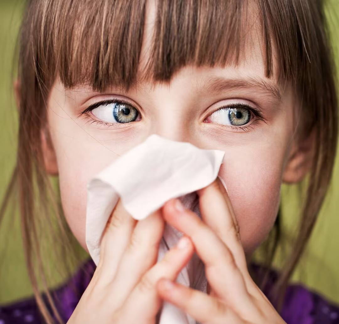  Dítě se dívá na stranu během smrkání – má alergickou rýmu, což ho velmi trápí