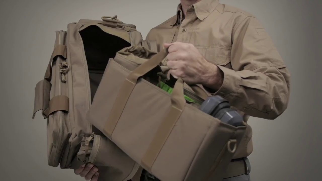 Person holding a tactical backpack and a bag, preparing for outdoor activities.