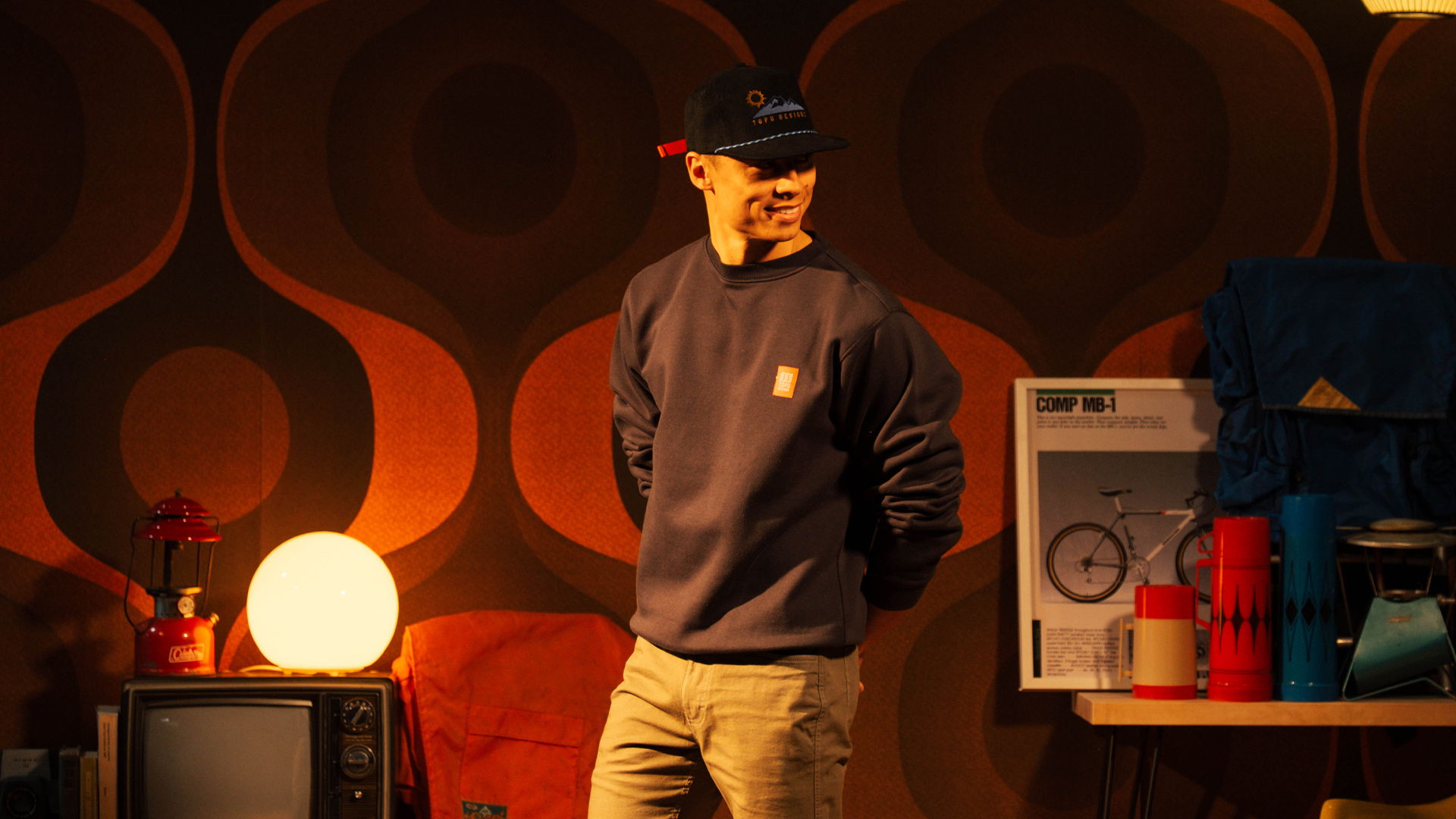 Person in casual clothing standing in a retro-themed room with soft lighting.