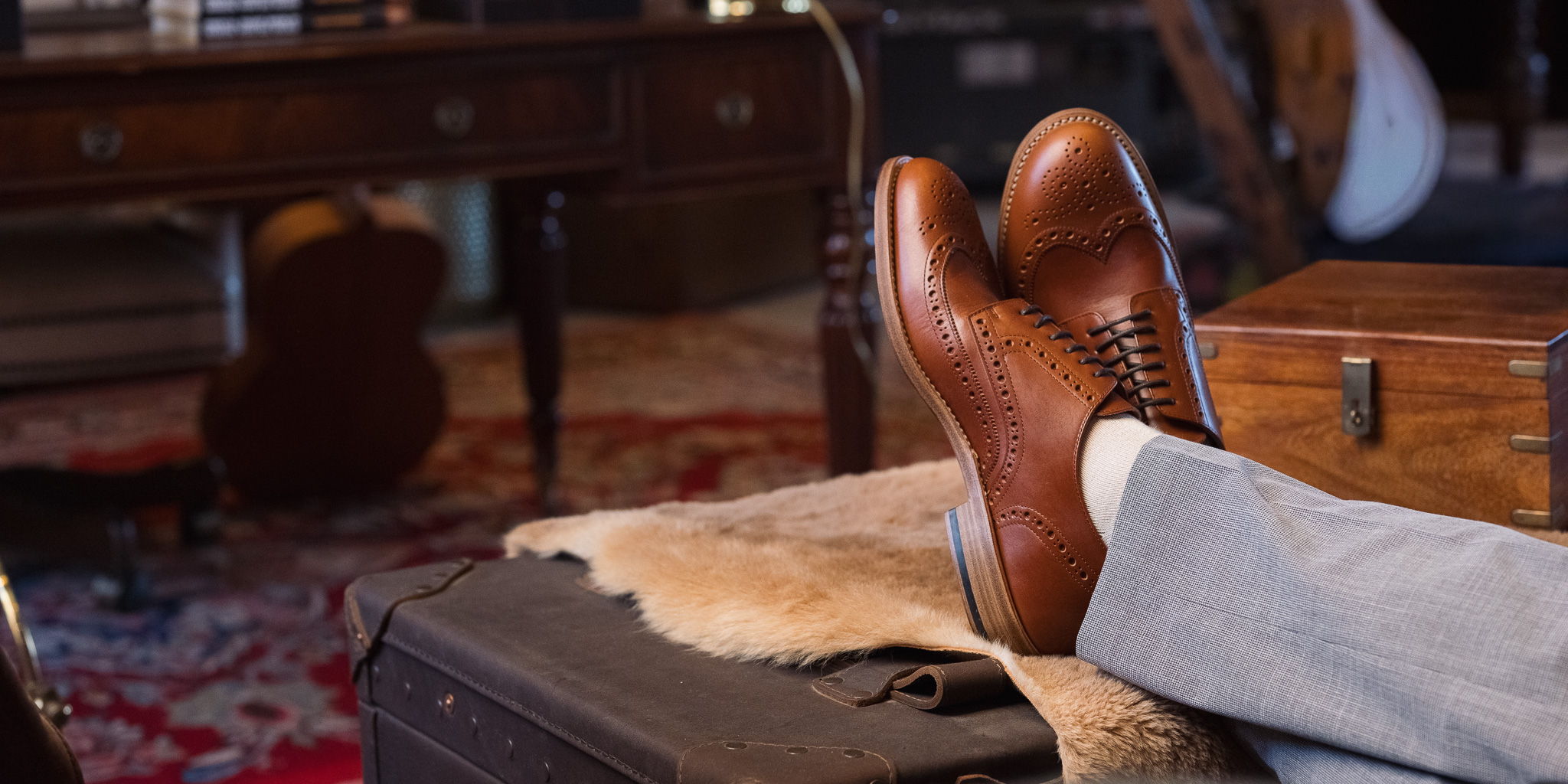 A pair of brown shoes resting on a suitcase in a cozy setting.