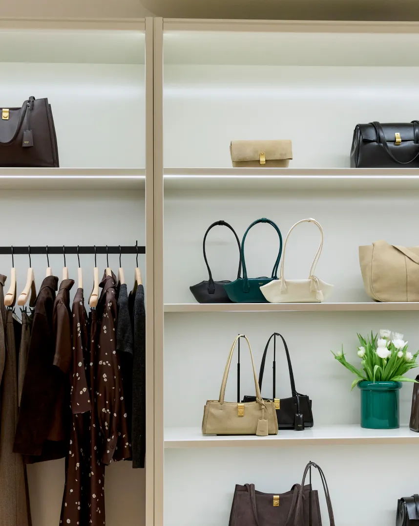 Shelves displaying various handbags and clothing in a retail setting.