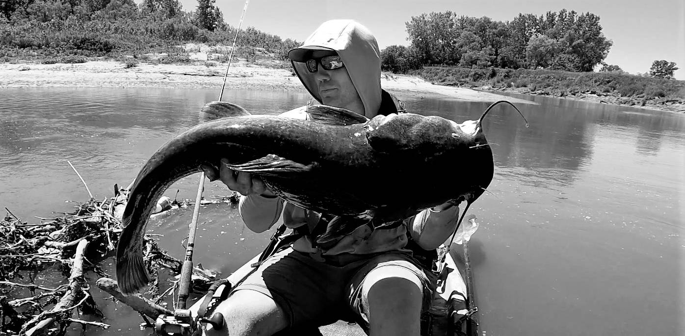 Spencer Bauer or River Certified holding a monster flathead catfish in hish kayak on the river.
