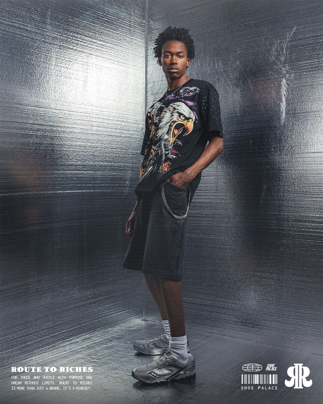 Person in graphic t-shirt and shorts, standing in a reflective environment.