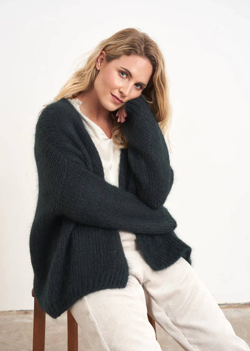 A model wearing a dark blue slouchy knitted cardigan over a white top and trousers