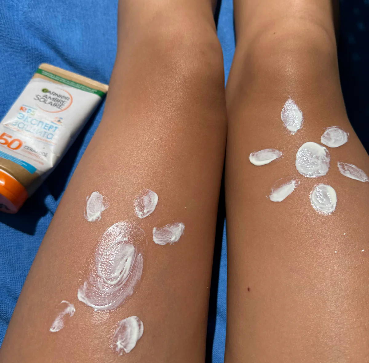Eine Frau hat sich mit Sonnencreme zwei Sonnen auf ihre Oberschenkel gemalt.