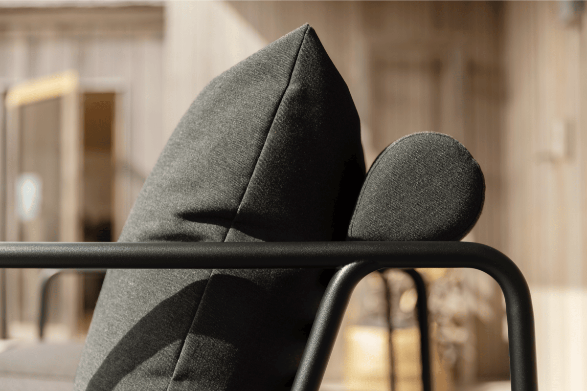 Close-up of black performance outdoor cushions on a powder-coated metal lounge chair, showing clean lines and durable upholstery details.