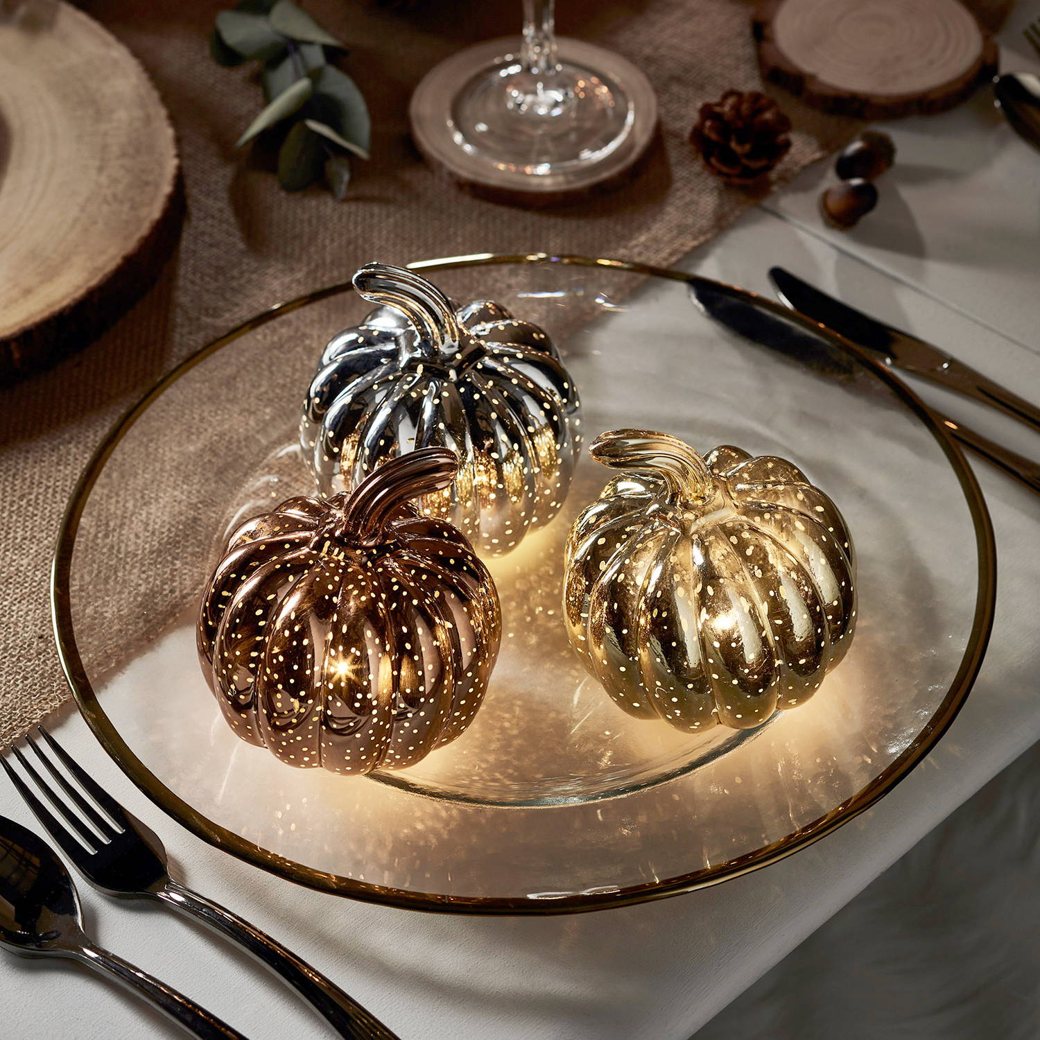 3 mini light up pumpkins on a plate as place settings for an autumn dining display.