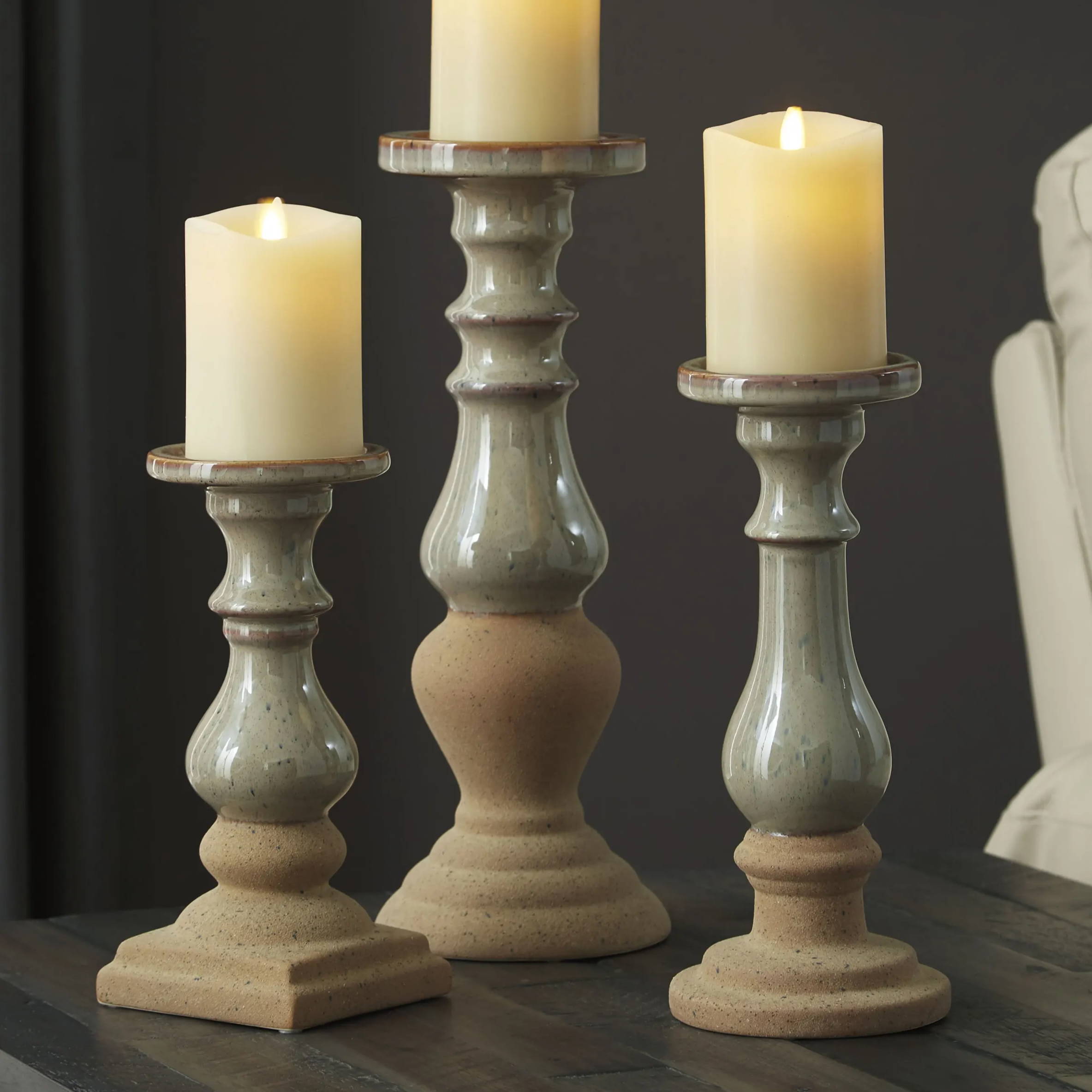 three lit candles sit on farmhouse-style candle holders.