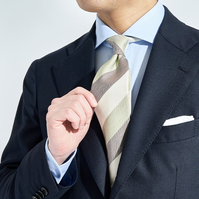 A man adjusting his striped tie while wearing a suit jacket.
