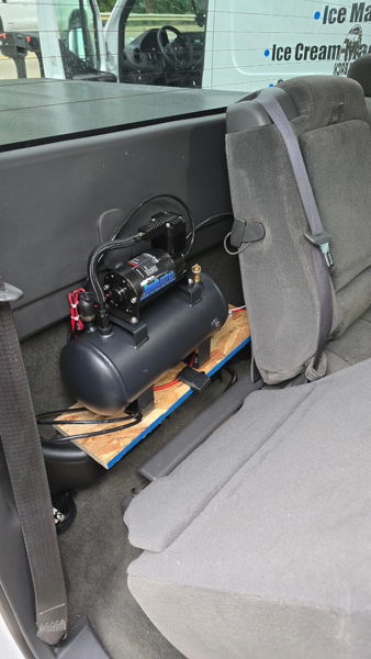 Air tank and compressor mounted behind rear seat inside Joshua's 2005 Chevrolet Silverado 1500 for the Flatlaw 127H kit, install photo 4