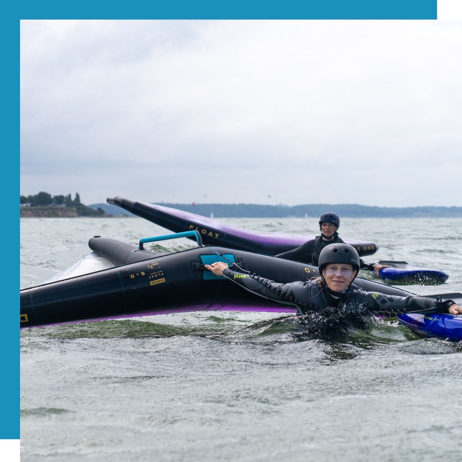 Two individuals in wetsuits Wingfoil on calm water.