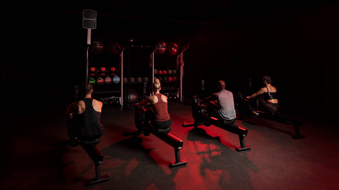 Exercisers lines up and working out on Heat Rowers in studio