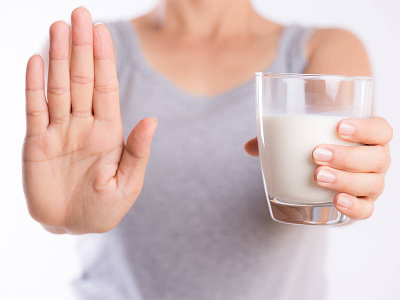 Een vrouw met een glas melk maakt een soort stop-gebaar met haar hand