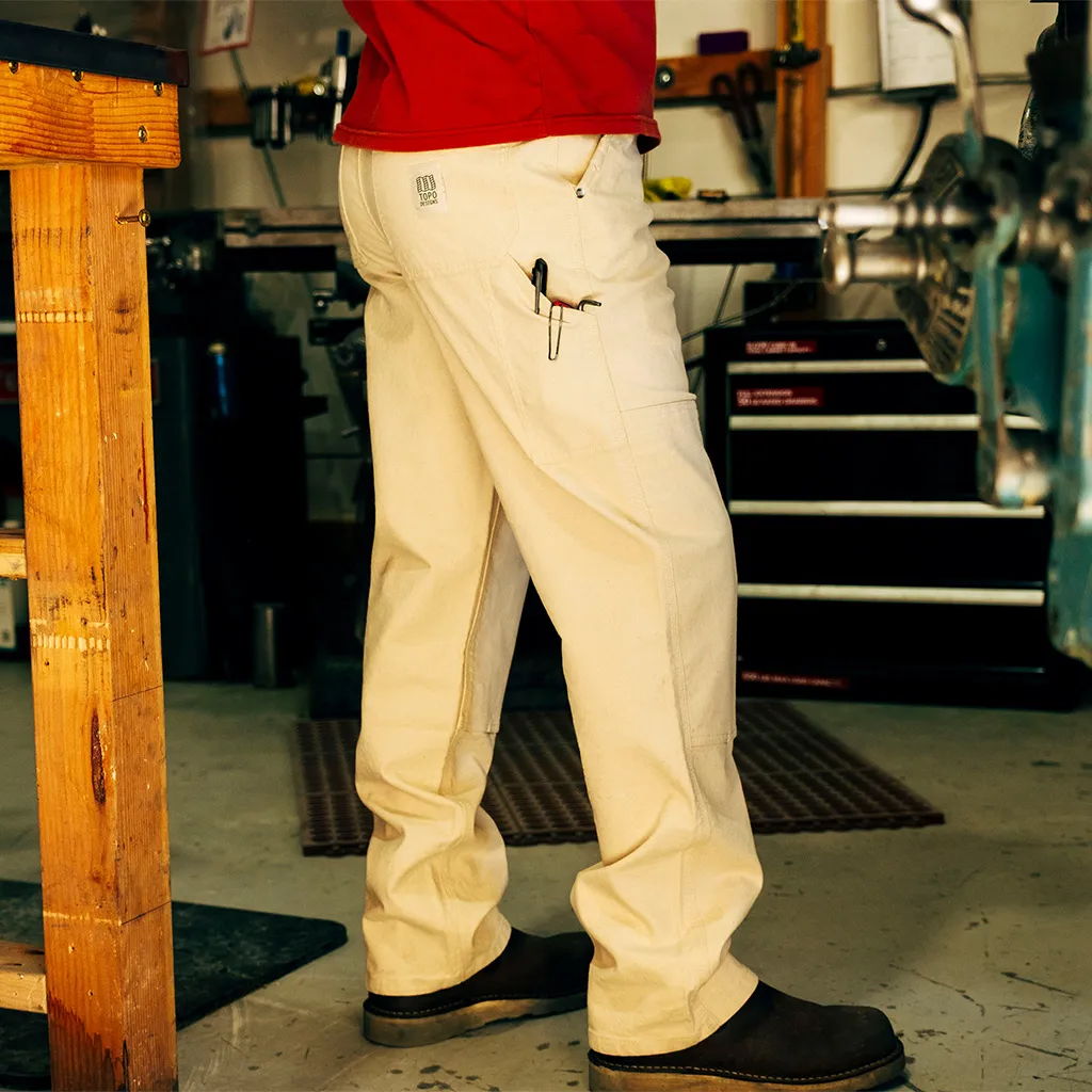 Person wearing beige pants and black shoes in a workshop setting.