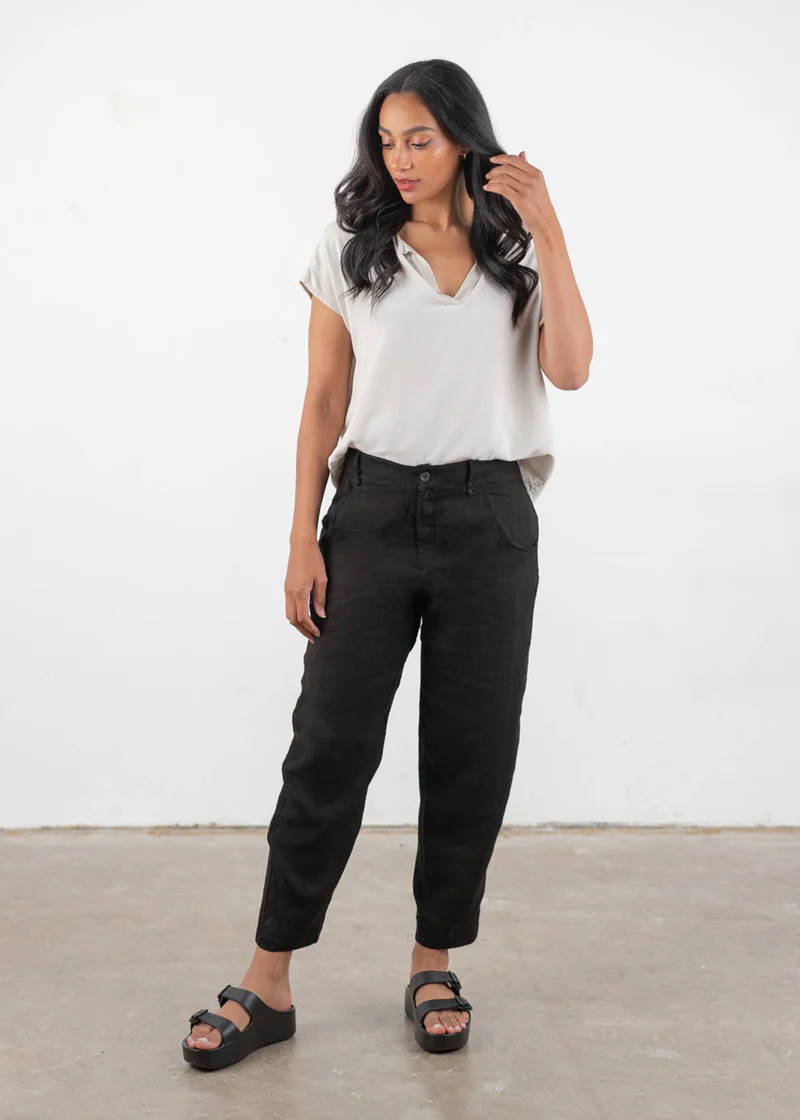 A model wearing a short sleeved oatmeal coloured t shirt over a pair of black linen trousers with black chunky platform buckle slides