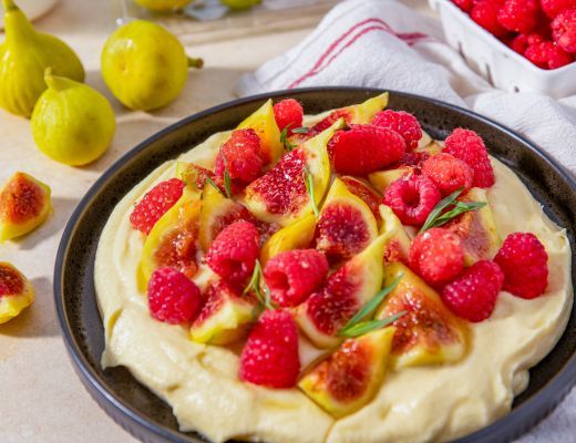 A fruit tart topped with raspberries and lemon slices.