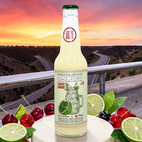 Bottle of lime soda with cherries and limes against a scenic sunset background.