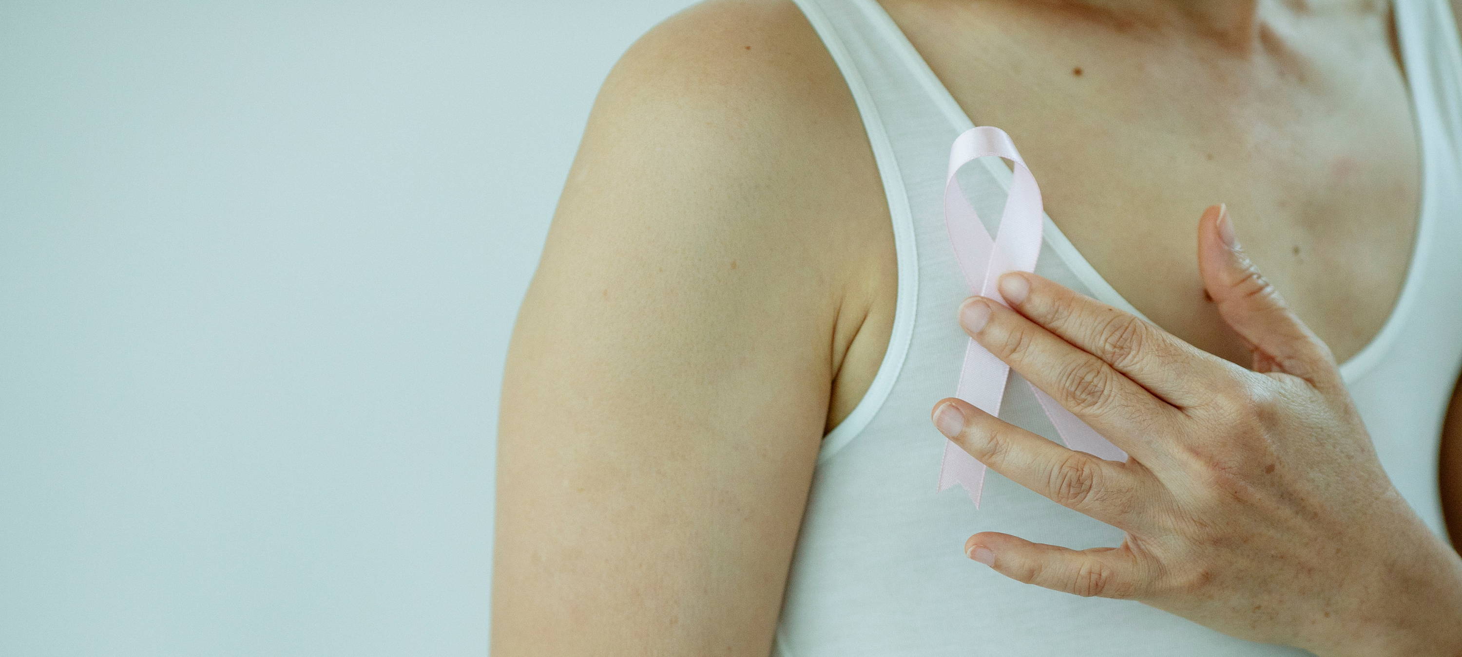 Frau, die rosa Schlaufe vor ihrer Brust hält, um Aufmerksamkeit für das Thema Brustkrebs zu schaffen.