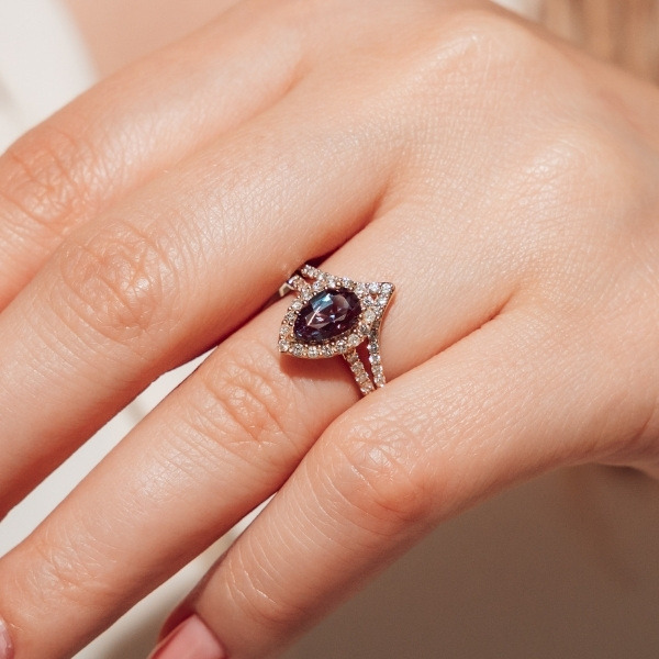 A diamond accented ring with a pear cut alexandrite center stone and matching diamond accented wedding band