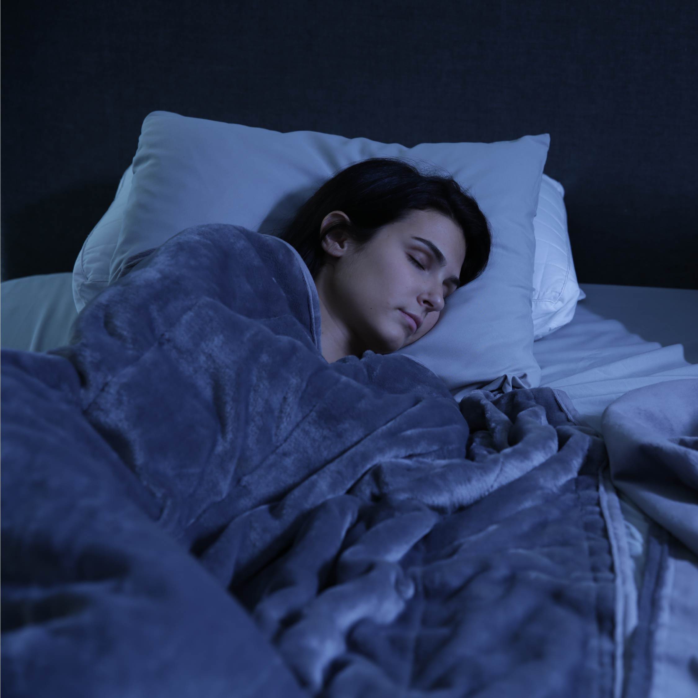 Woman sleeping peacefully with the Tuc Warm Weighted Blanket.