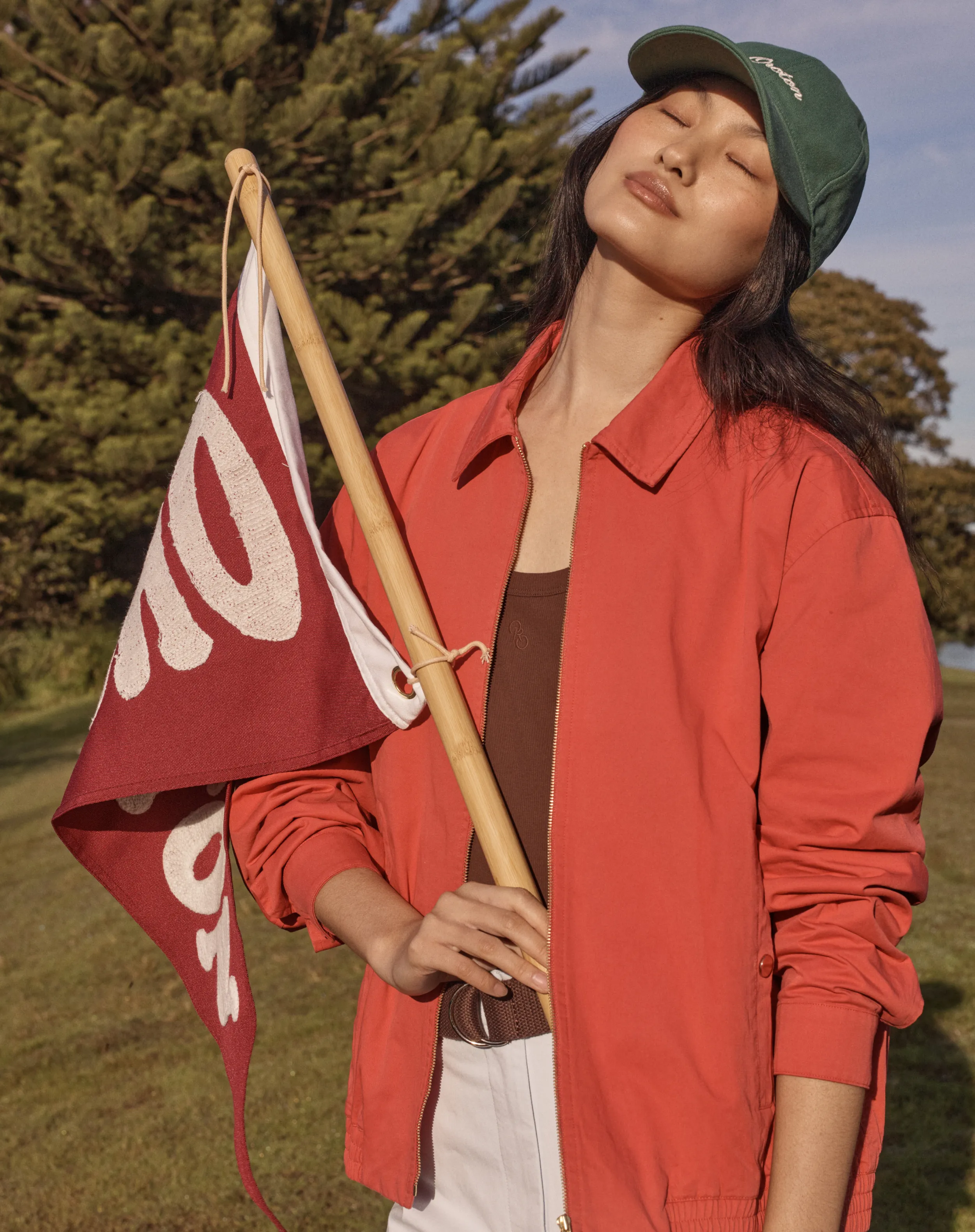 A woman in a red jacket holds a flag outdoors.