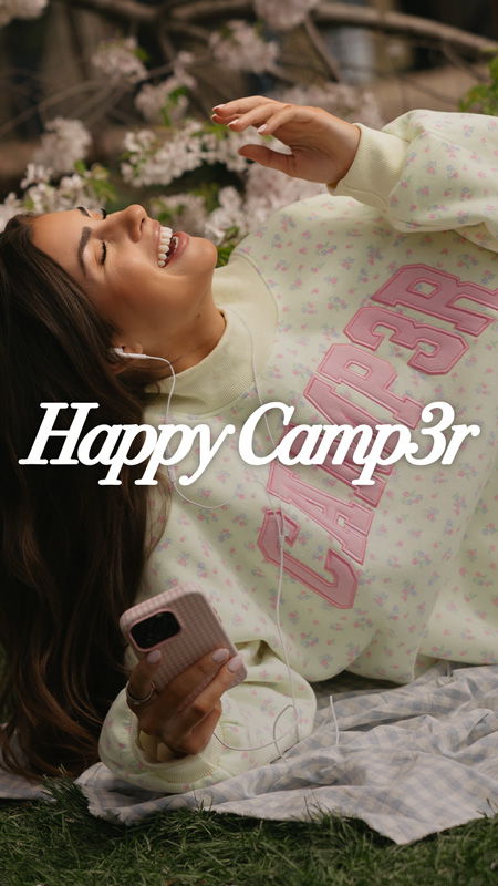 Young woman smiling while listening to music outdoors in a cozy sweater.