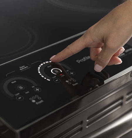 Woman controlling oven with touch controls.