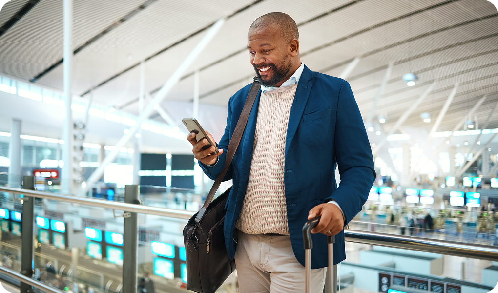 Man in a suit checking his phone at the airport.