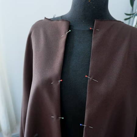 glass head pins on a cloak that is hanging on a dress form