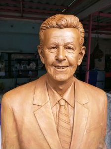 A cast of a man wearing a suit and smiling