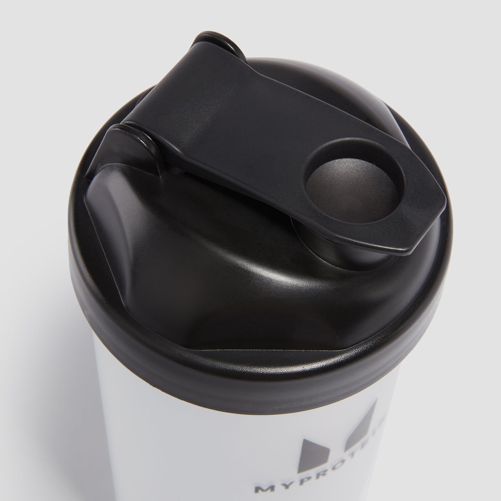 Black lid of a white travel mug with a drinking spout.