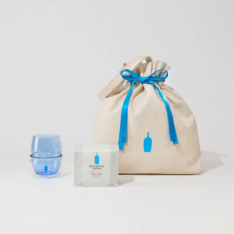 Cosmetic items in a cream bag with blue ribbon and logo.