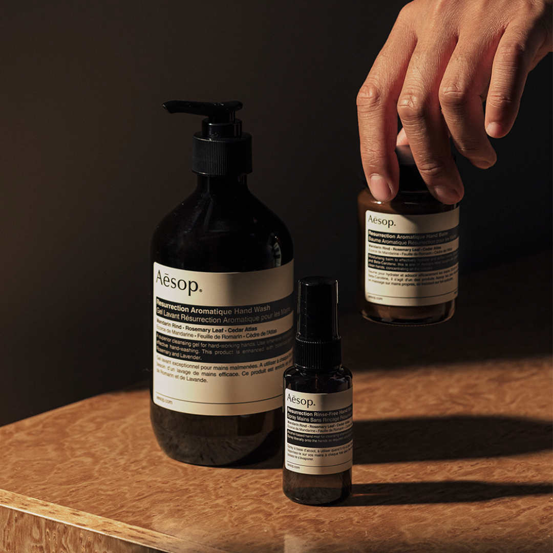 Hand holding skincare products on a wooden surface.