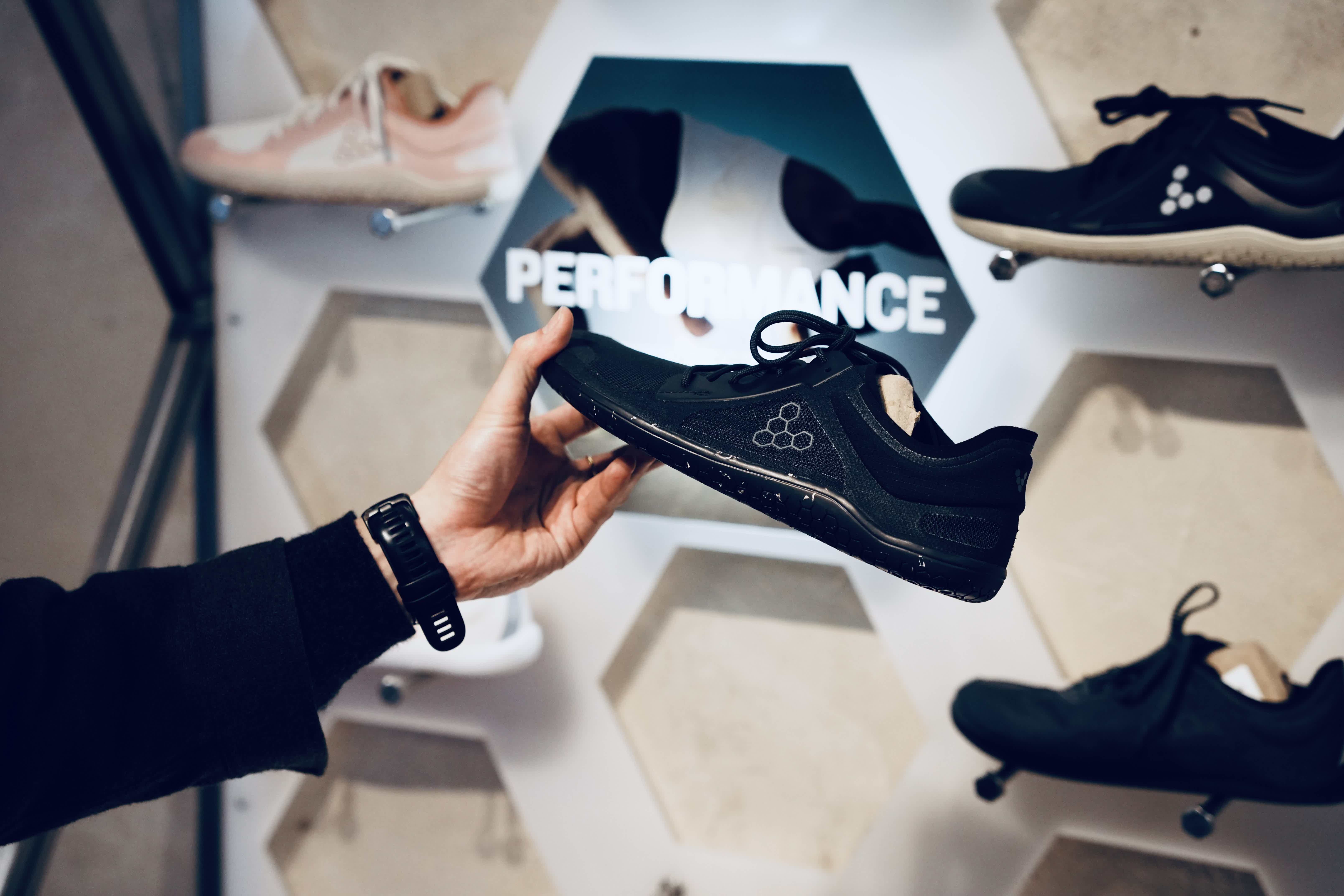 A person holding a shoe in a display of athletic footwear.