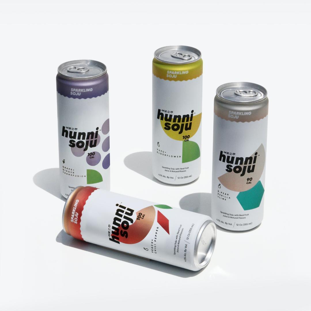 Four cans of Hunni Soju in various flavors against a white background.