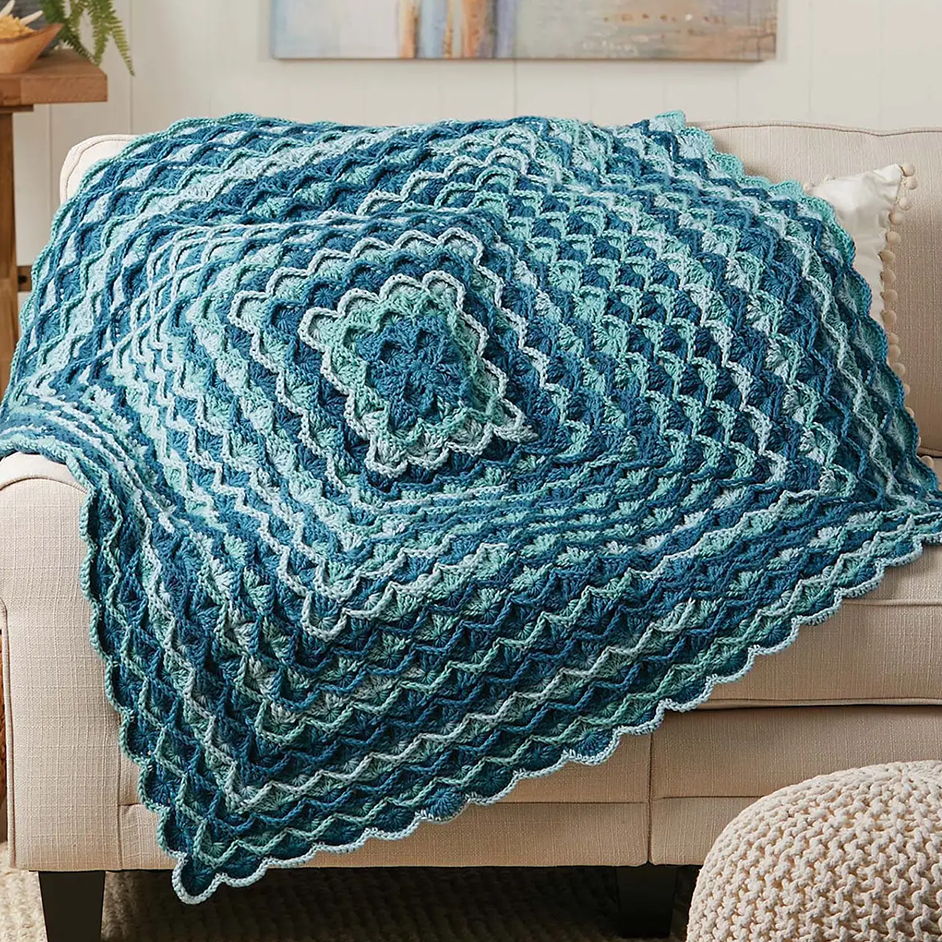 A knitted blue and green blanket draped over a couch.