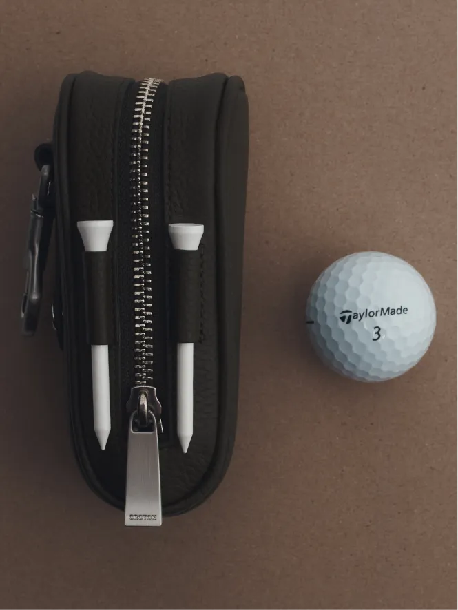 Golf tee case with two tees and a golf ball.
