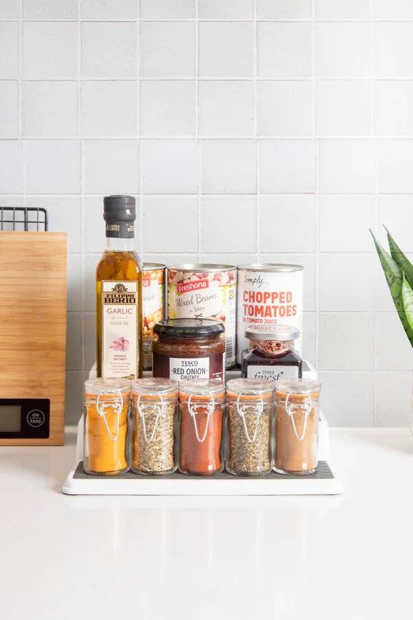 Tins, spices, and a bottle of oil on a tiered shelf organiser.  