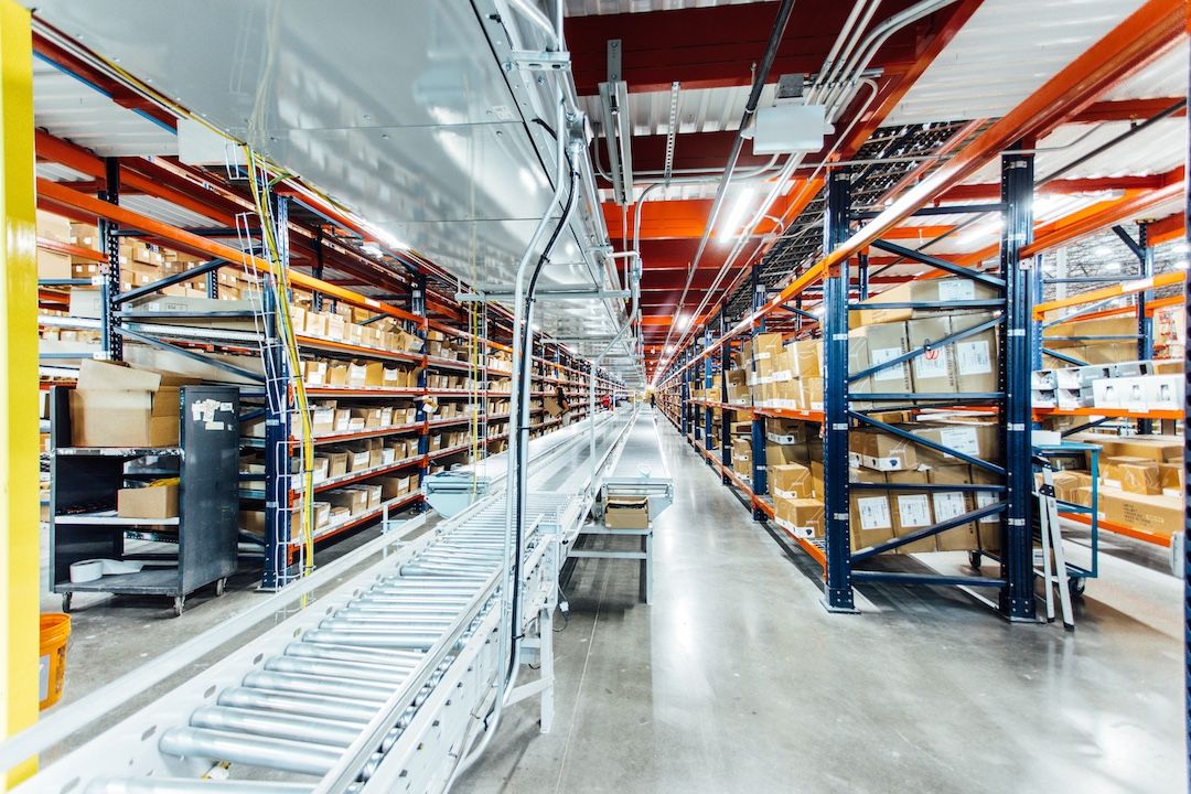 Conveyor with a pallet rack mezzanine over it