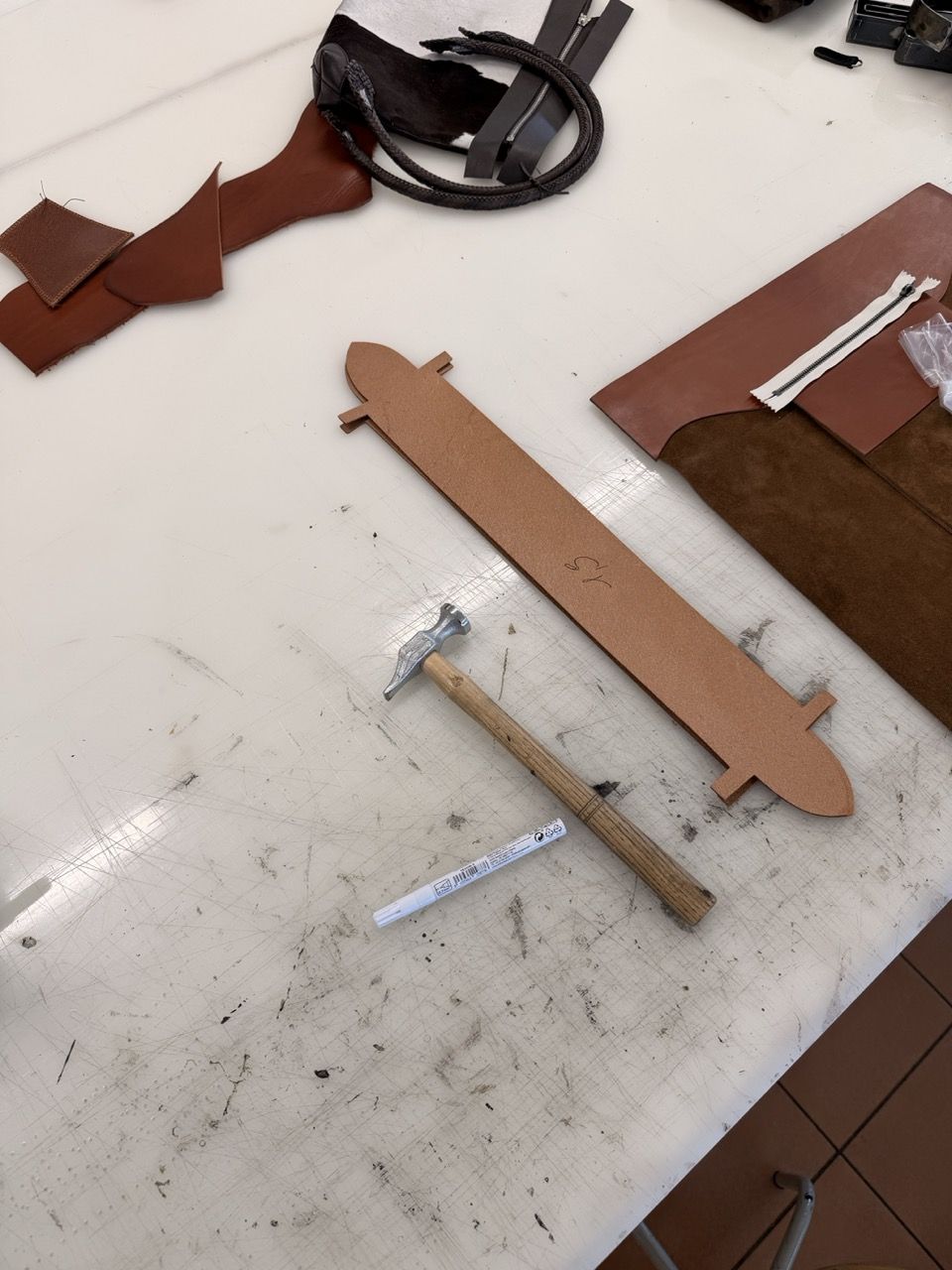 Leatherworking tools and materials on a worktable.